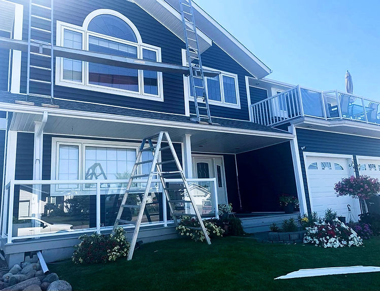 A house with a ladder leaning against its side and another ladder placed on the roof.