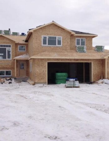 A new home build with a garage and snow on the ground.