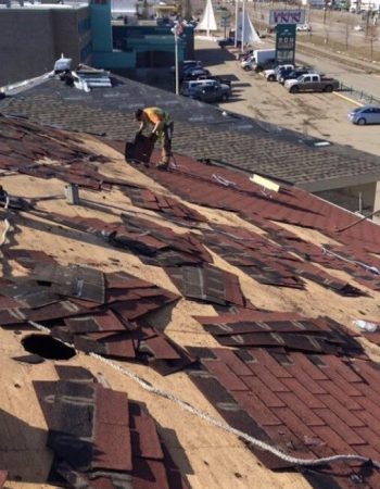 Workers repairing a roof, using tools and materials, to fix damages caused by wear and tear.