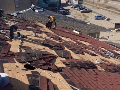 Workers repairing a roof, using tools and materials, to fix damages caused by wear and tear.