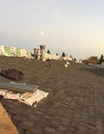 A large pile of shingles next to a house under construction, ready to be used for a roofing job.