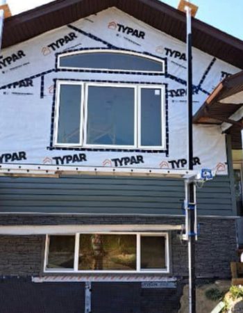 A house under construction with siding and windows.