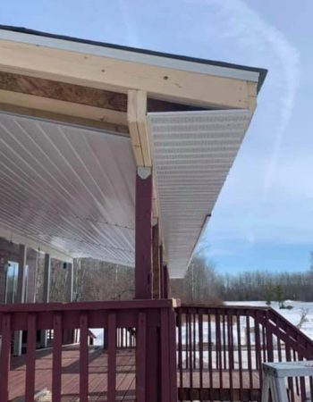 A wooden deck under a metal roof on a porch.