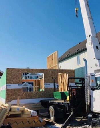 A crane lifting a house onto a truck.