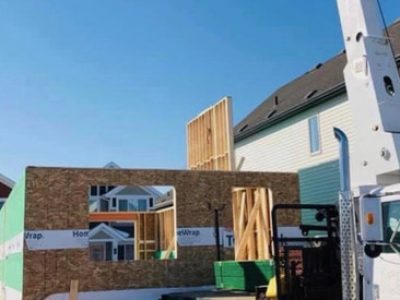 A crane lifting a house onto a truck.