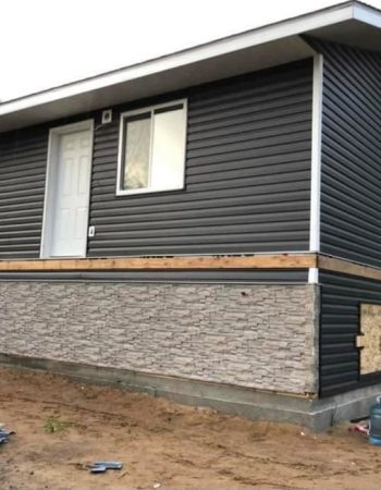 A house under construction with siding and a window.