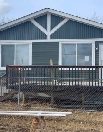 A house with a wooden fence and a chain link fence in front of it.